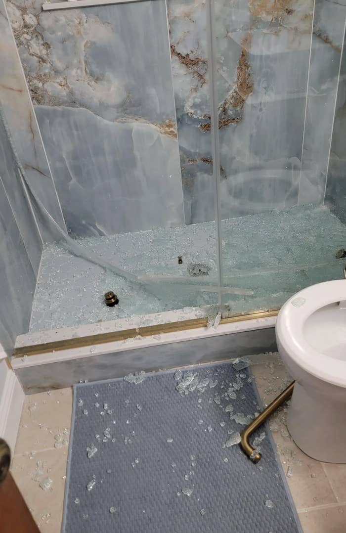 A glass shower door shattered, with shards everywhere