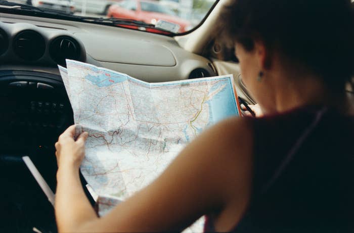 Person looking at a large map inside a car. The map shows a detailed view of roads and areas, suggesting the person might be planning a journey or navigating