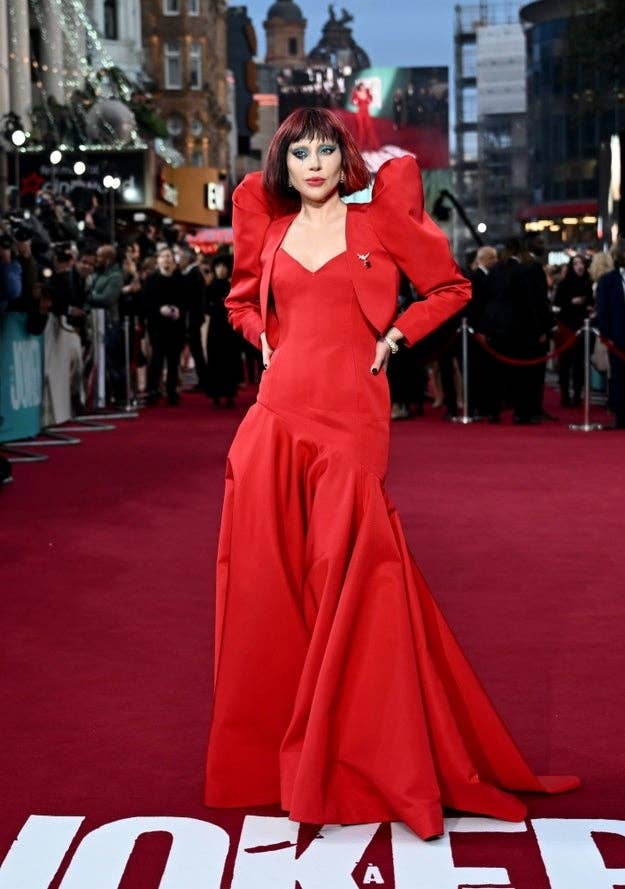 Millie Bobby Brown on the red carpet in a floor-length, red gown with long, puffy sleeves and dramatic makeup