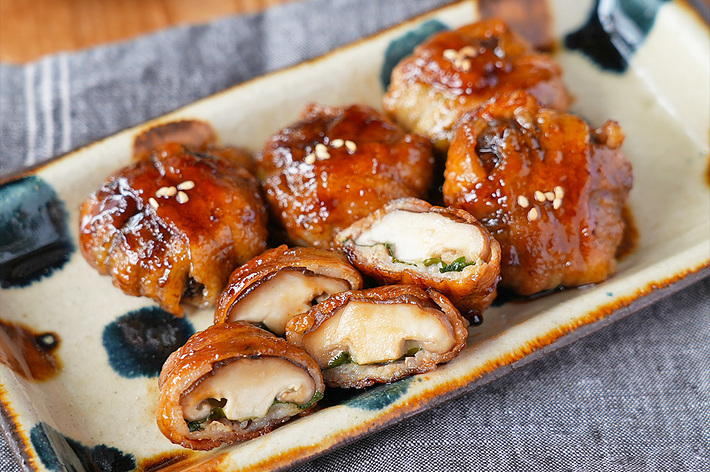 お皿に盛り付けられた、カリっと焼かれた肉巻き料理が載っている。