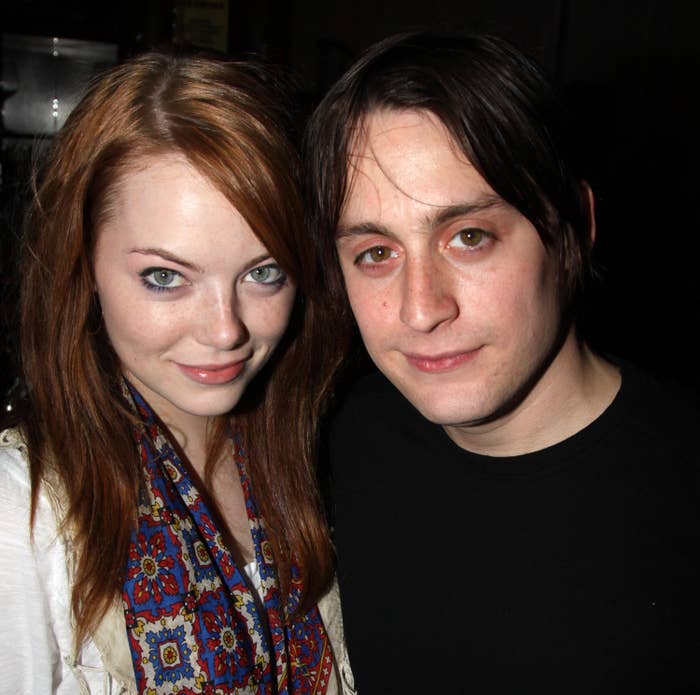 Emma Stone in a floral scarf and top posing with Kieran Culkin in a dark shirt at an event