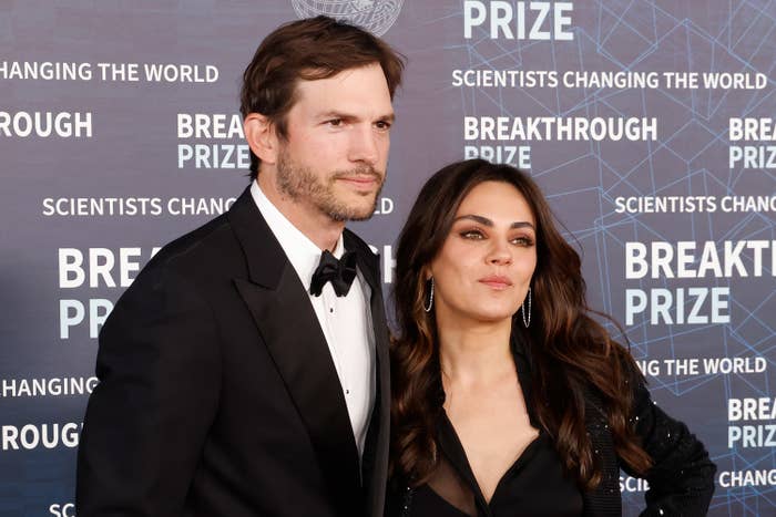 Ashton Kutcher in a tuxedo and Mila Kunis in an elegant dress pose together at the Breakthrough Prize event