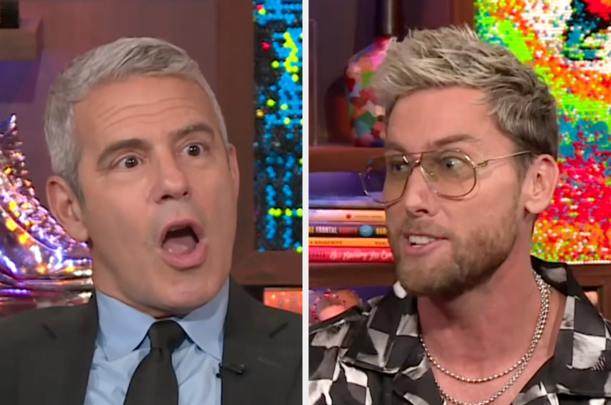 Andy Cohen, in a suit and tie, appears surprised next to Lance Bass, in glasses and a patterned shirt, during an interview