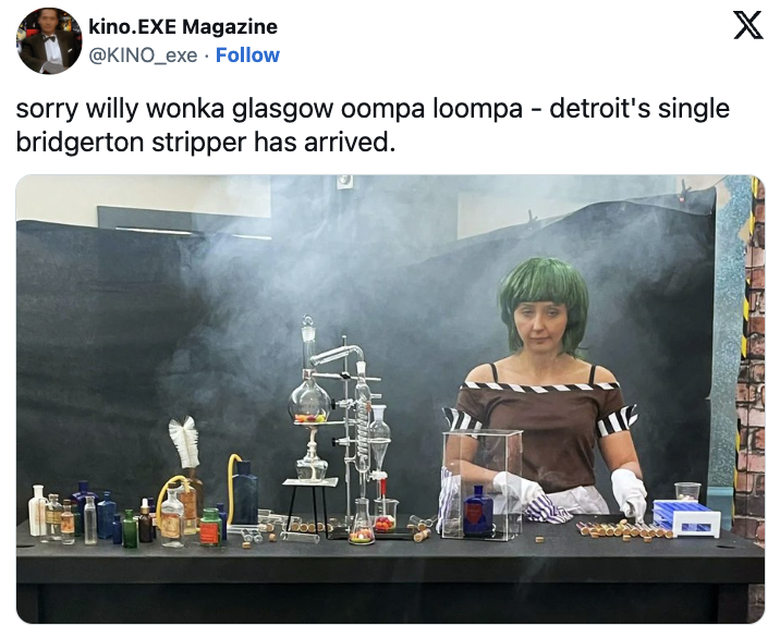 A woman with a green wig and steam-punk style outfit stands behind a laboratory setup with various bottles, tubes, and an alembic on a table. Text above reads, "sorry willy wonka glasgow oompa loompa - detroit's single bridgerton stripper has arrived."