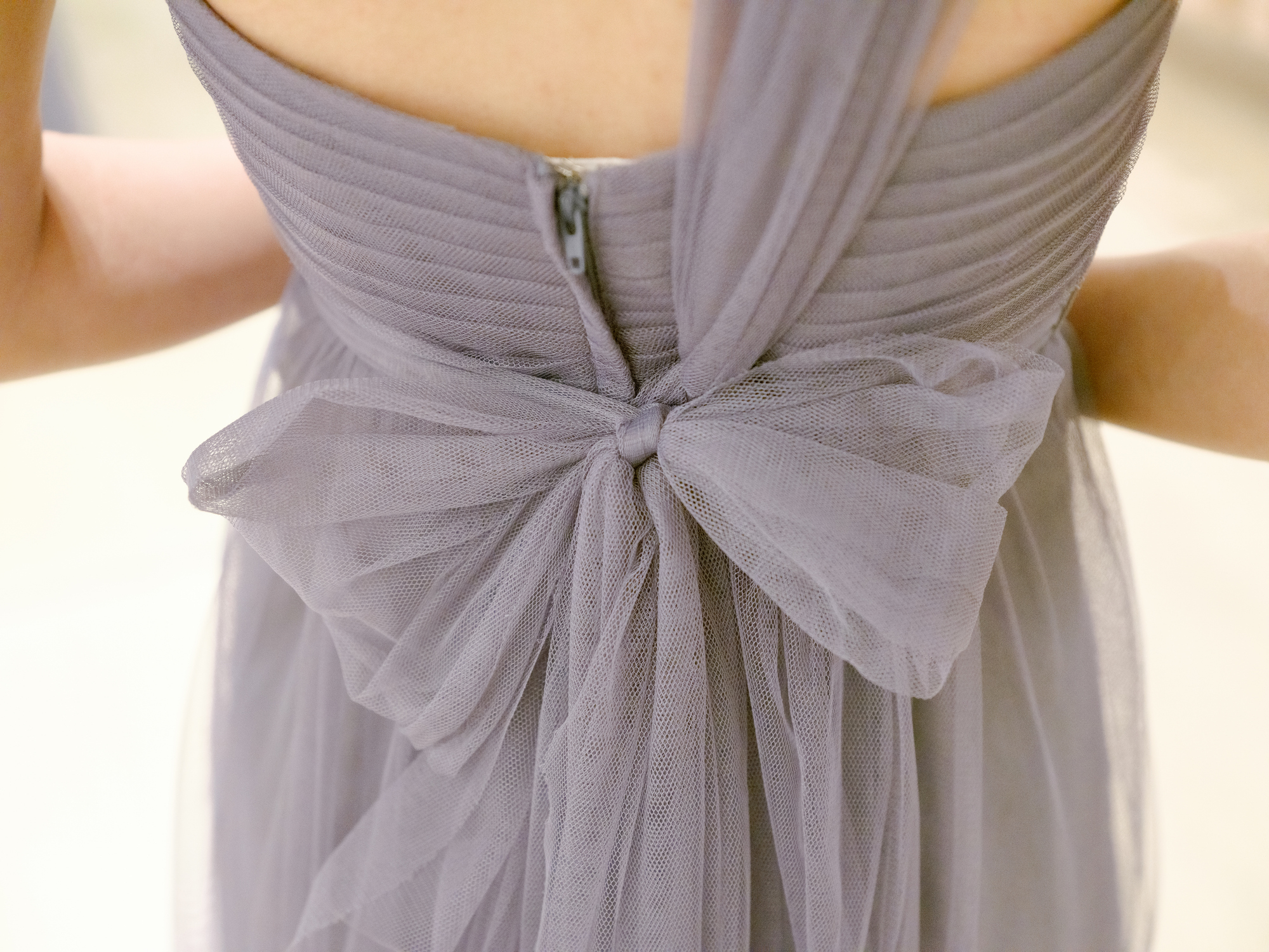 Back view of a bride's dress with a large bow at the waist, highlighting the intricate texture and design