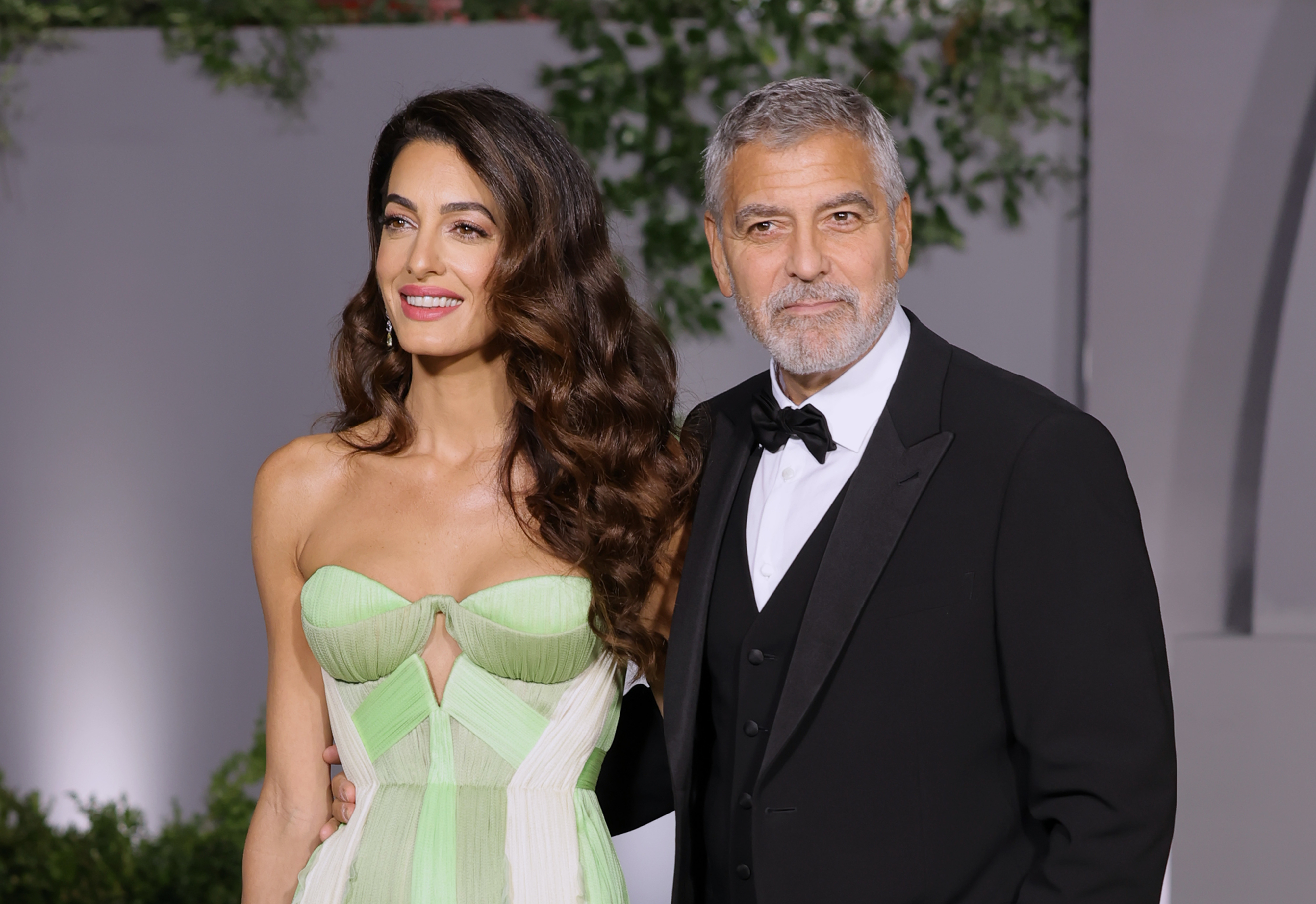 Amal Clooney, in a strapless gown, and George Clooney, in a black tuxedo, pose together on the red carpet