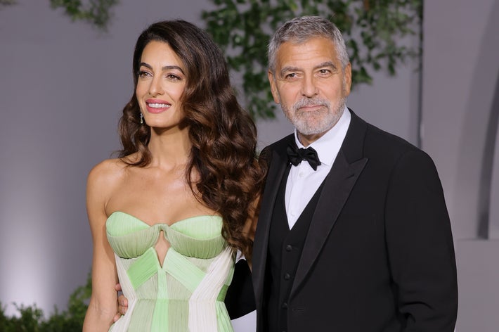 Amal Clooney, in a strapless gown, and George Clooney, in a black tuxedo, pose together on the red carpet