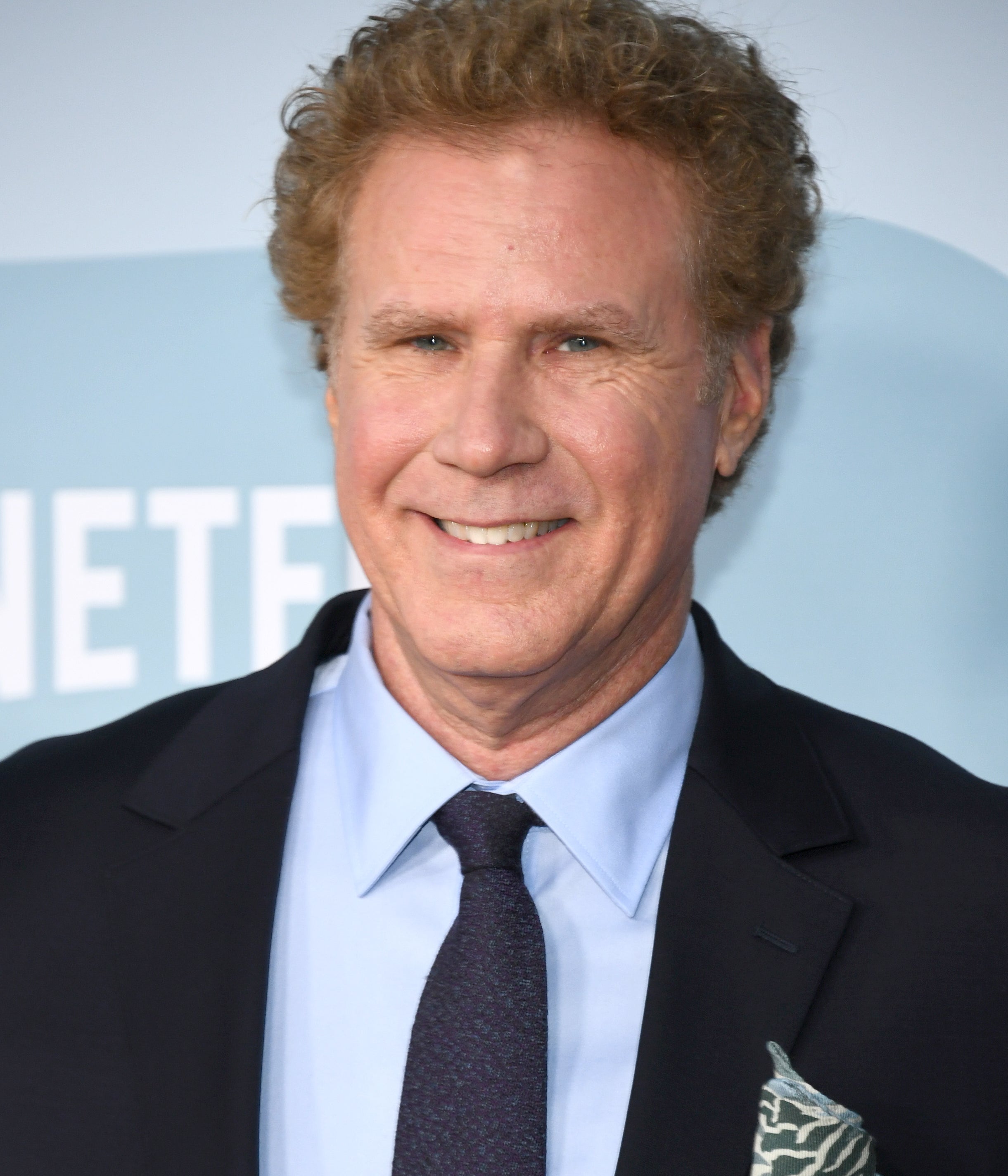 Will Ferrell at a public event, smiling while dressed in a suit and tie with a patterned pocket square