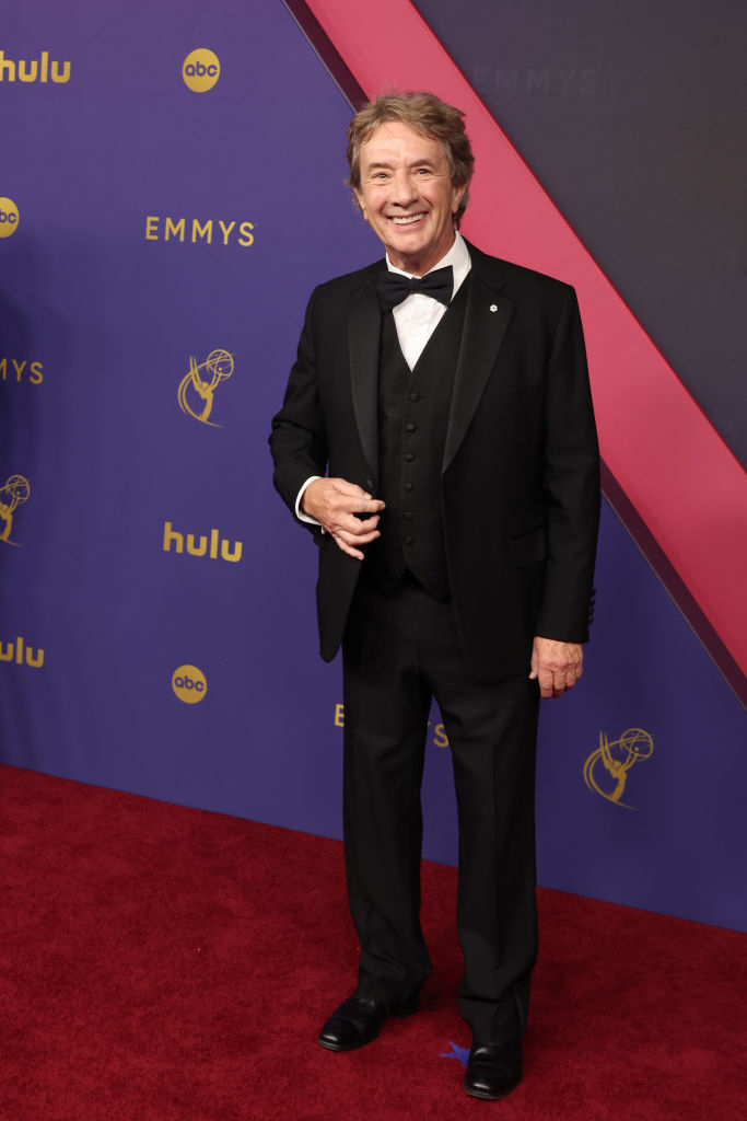 Martin Short posing in a black tuxedo with a bow tie at the Emmys red carpet event