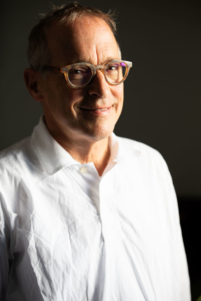 A person in glasses and a white shirt smiles at the camera