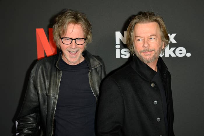 Dana Carvey, in a leather jacket, and David Spade, in a coat, smile while posing together at a Netflix event