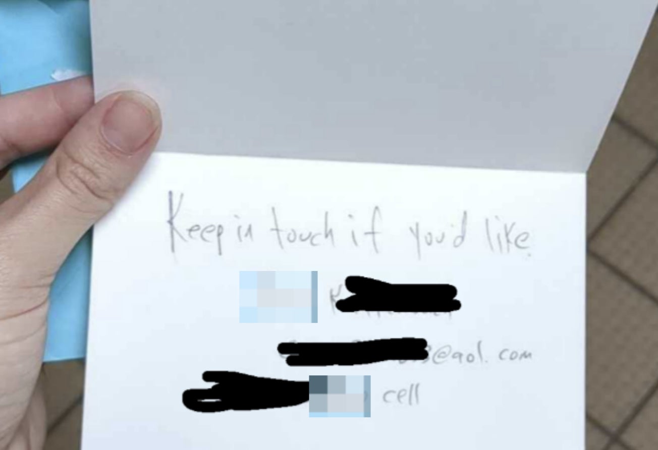 A hand holding an open card with the handwritten message: "Keep in touch if you’d like" followed by redacted email address and phone number