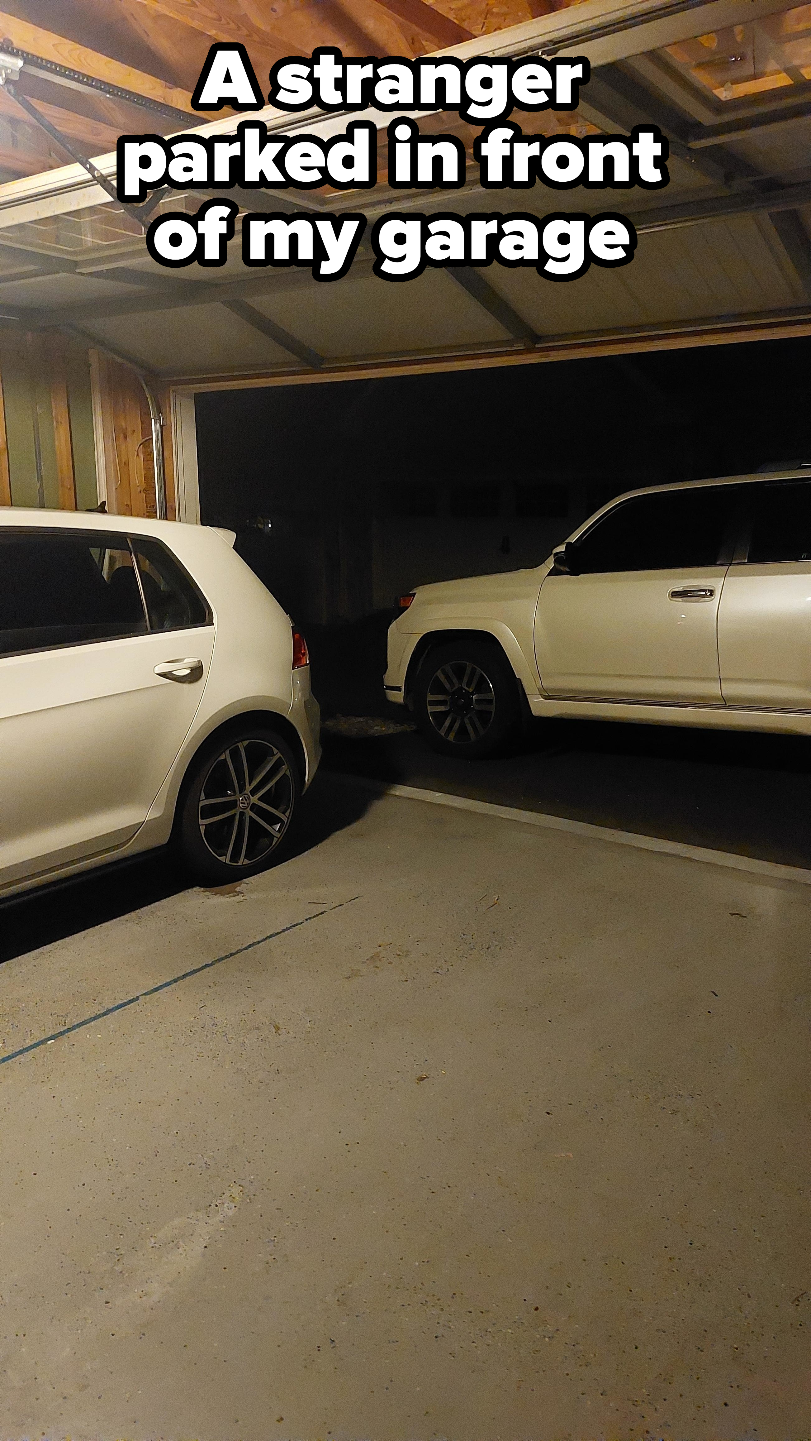Two white cars are parked inside a garage with the door partially open. The left car is a hatchback, and the right one is an SUV