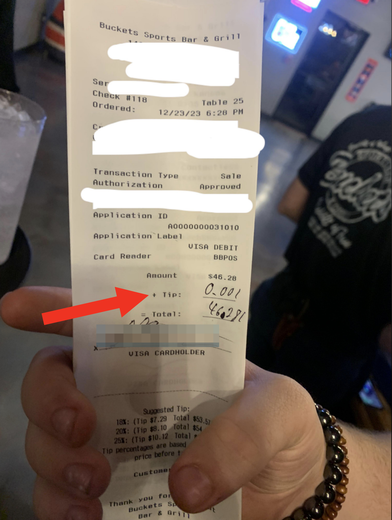 A person holds a receipt from Buckets Sports Bar &amp;amp; Grill; the transaction, totaling $46.28, has a tip of $0.001 added, bringing the total to $46.281