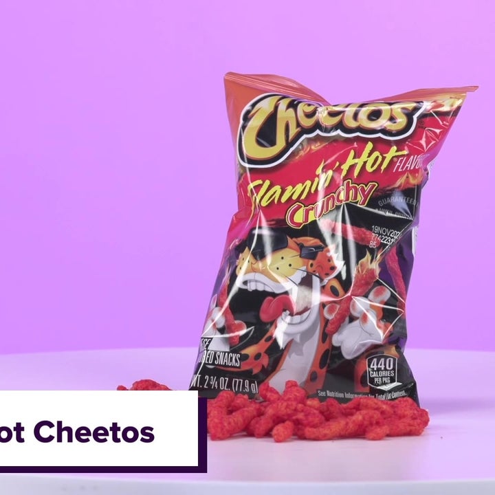 Bag of Flamin' Hot Cheetos placed on a white table with some Cheetos scattered in front of the bag. Text "Flamin' Hot Cheetos."
