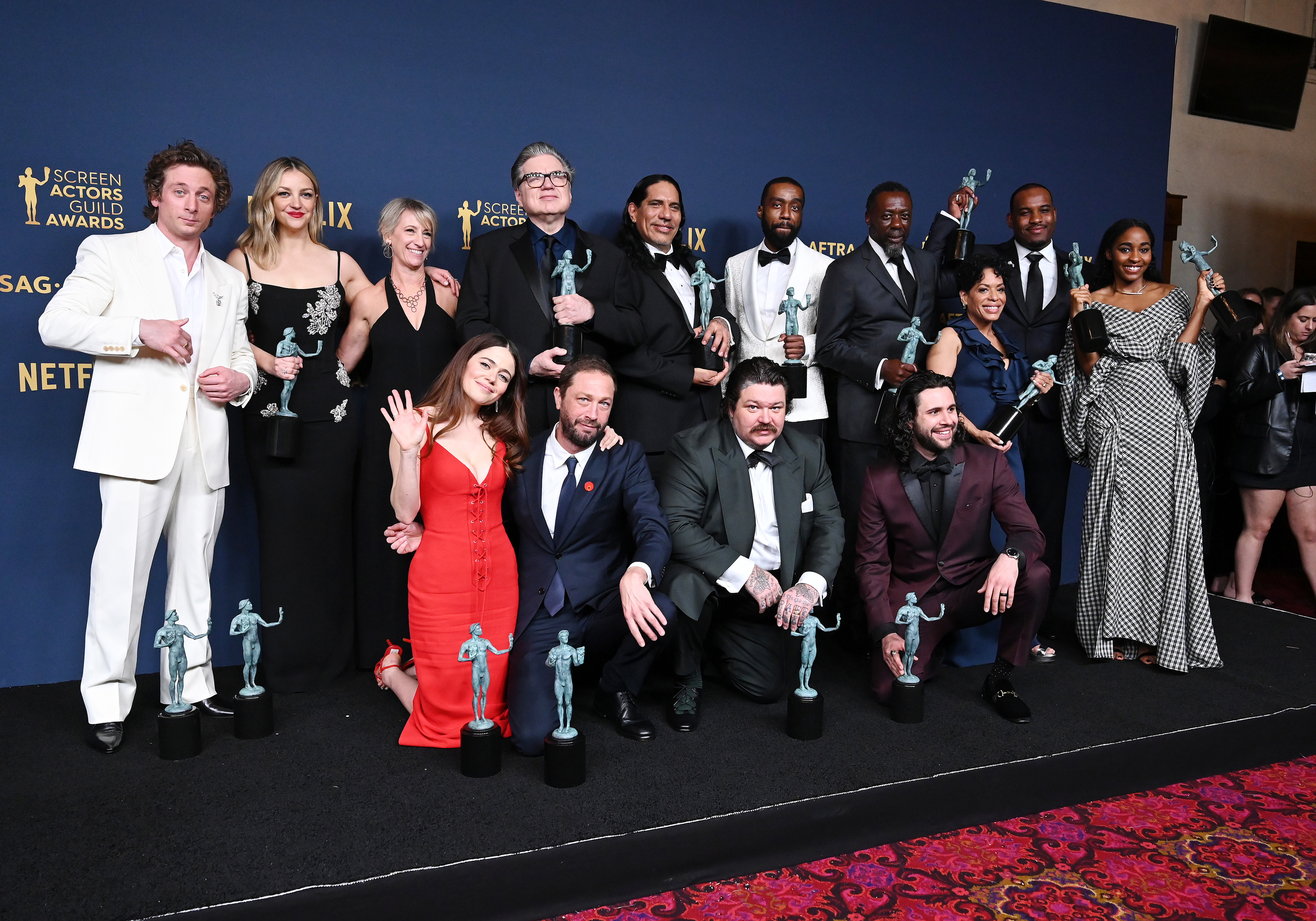 The cast of The Bear holding SAG Awards in front of a backdrop