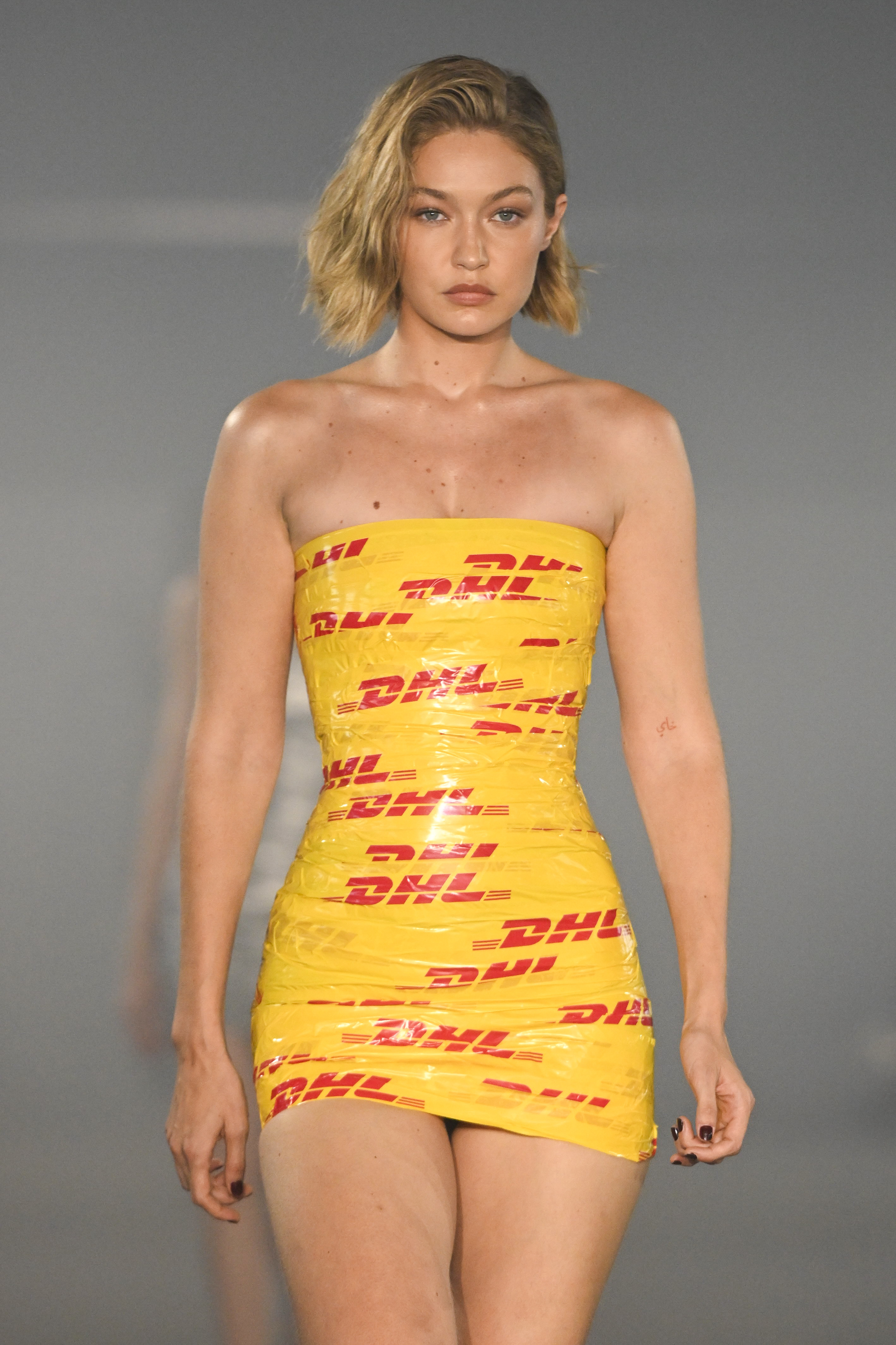 Gigi Hadid on the runway in a strapless mini dress made of DHL-branded tape