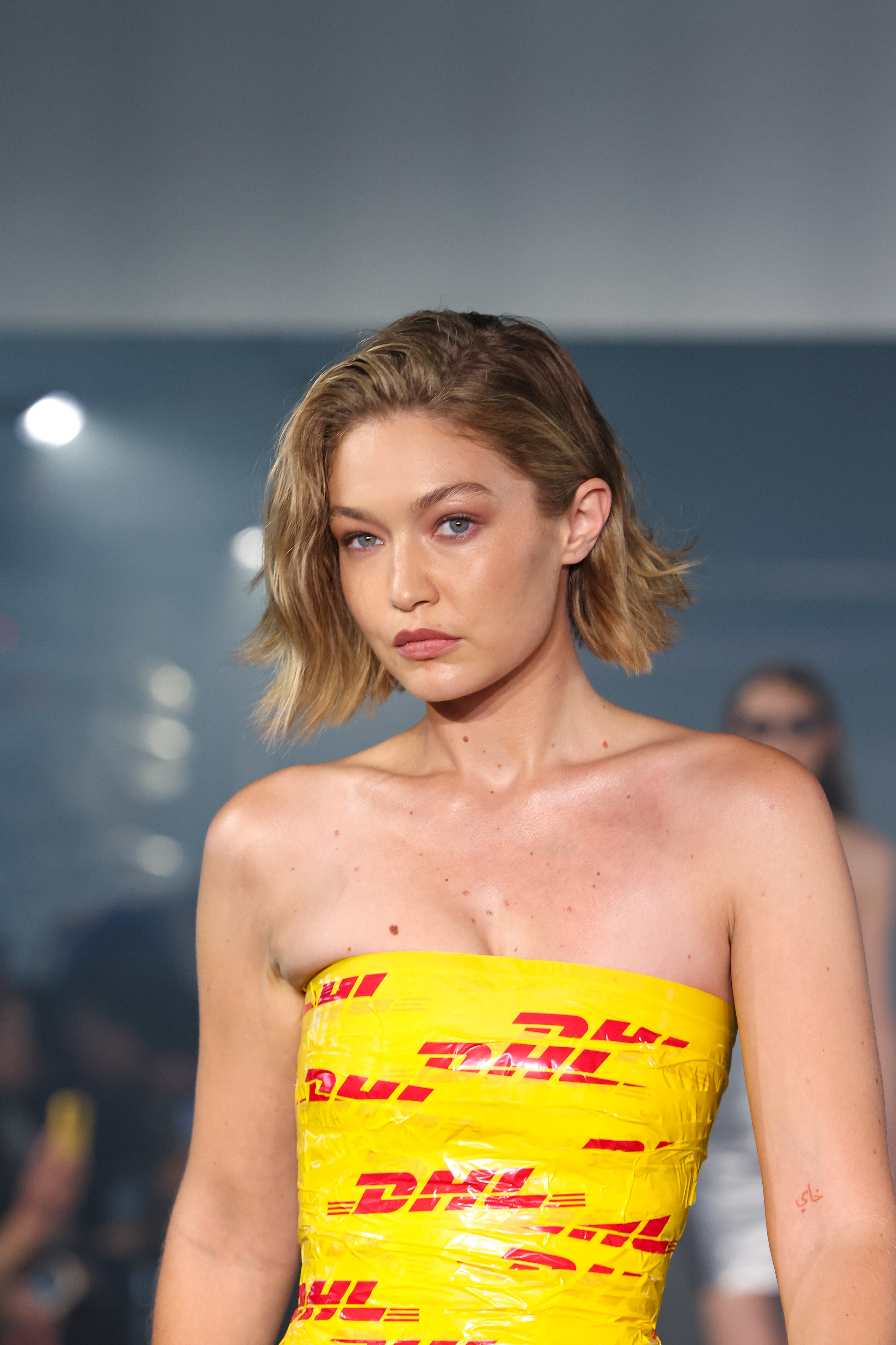 Gigi Hadid walks the runway in a strapless dress featuring DHL branding