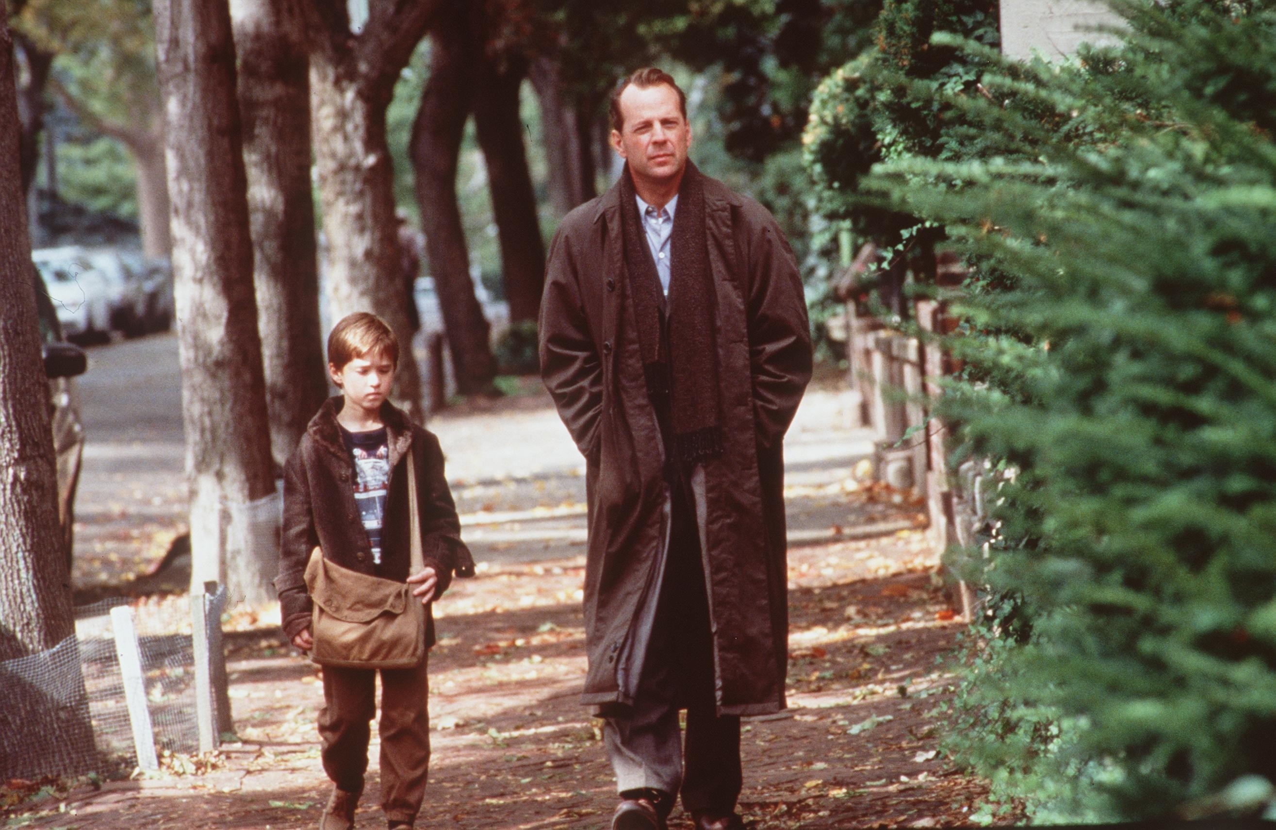 Haley Joel Osment and Bruce Willis walk on a tree-lined path in The Sixth Sense