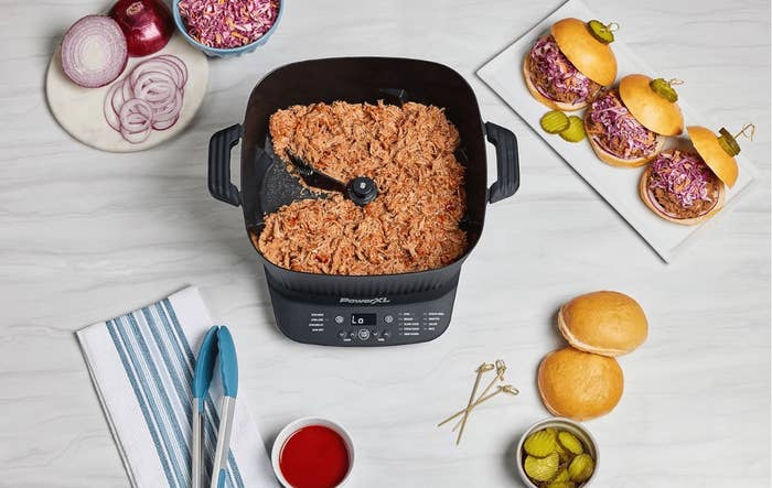 Panasonic dilatory cooker shredded pork, sliced onions, reddish cabbage slaw, sandwich buns, and pickles connected a achromatic antagonistic with serving tongs and cloth