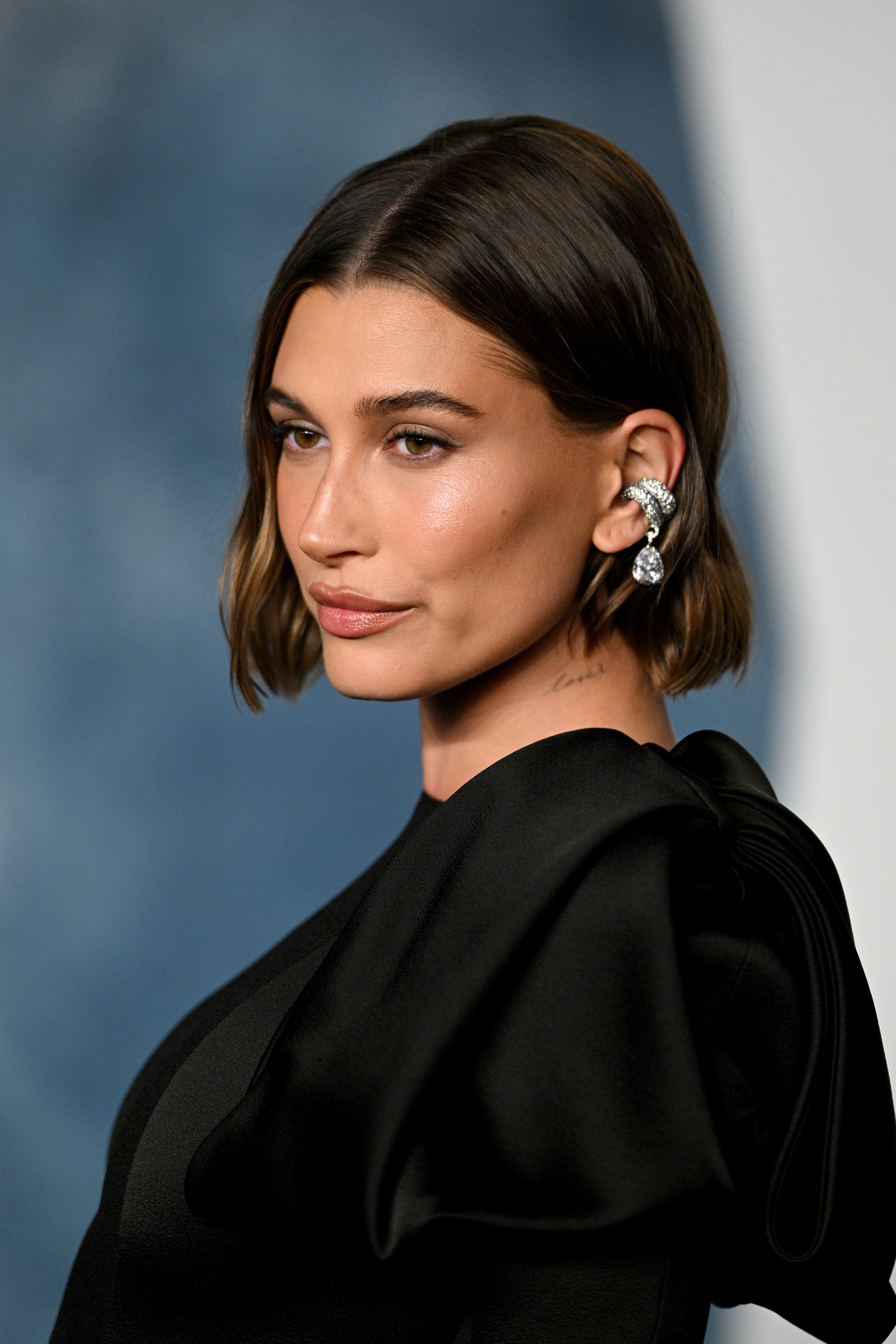 Hailey Bieber in a stylish black dress with statement earrings at a formal event