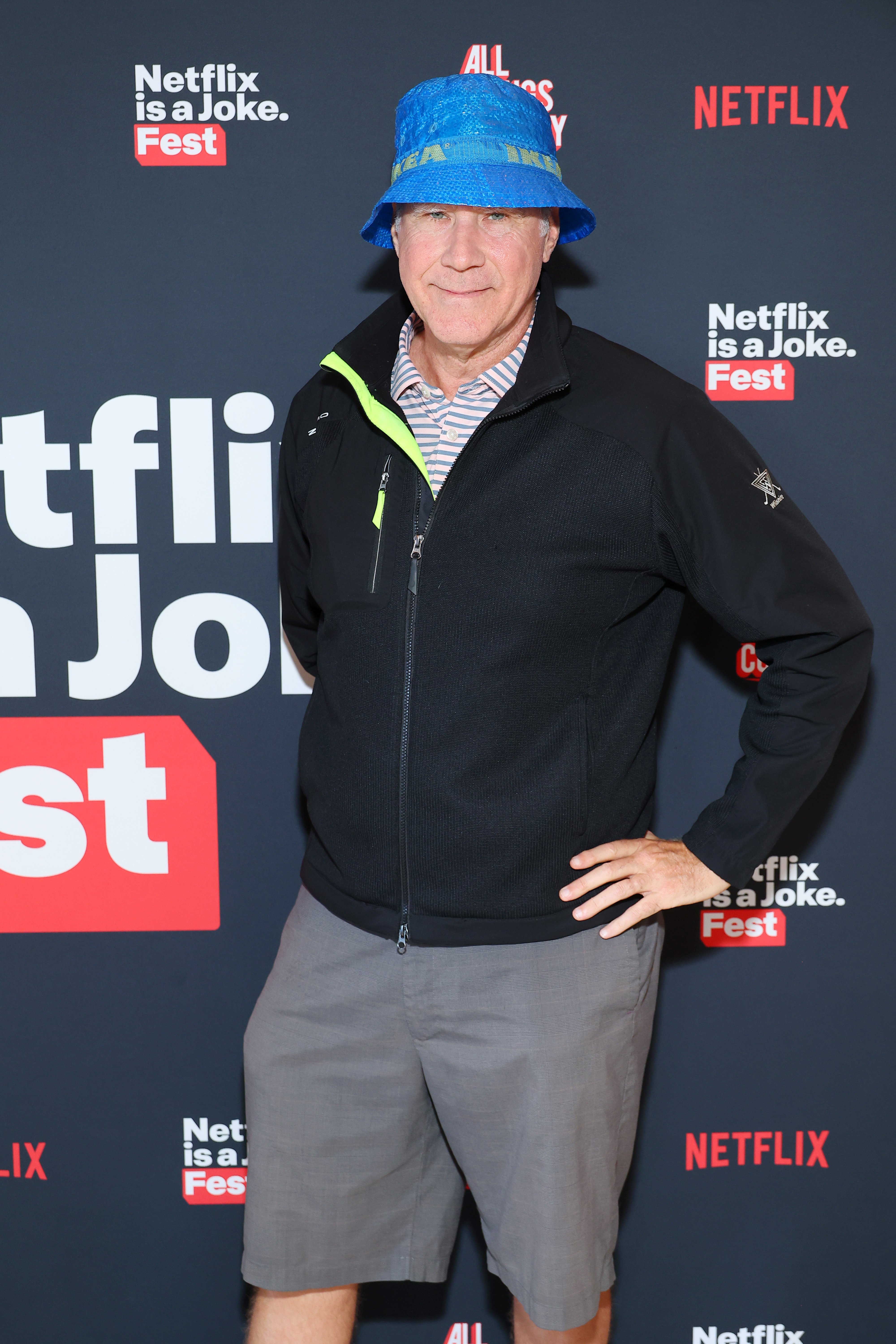 Person in a casual outfit with a blue bucket hat and shorts poses on the red carpet at the Netflix is a Joke Fest