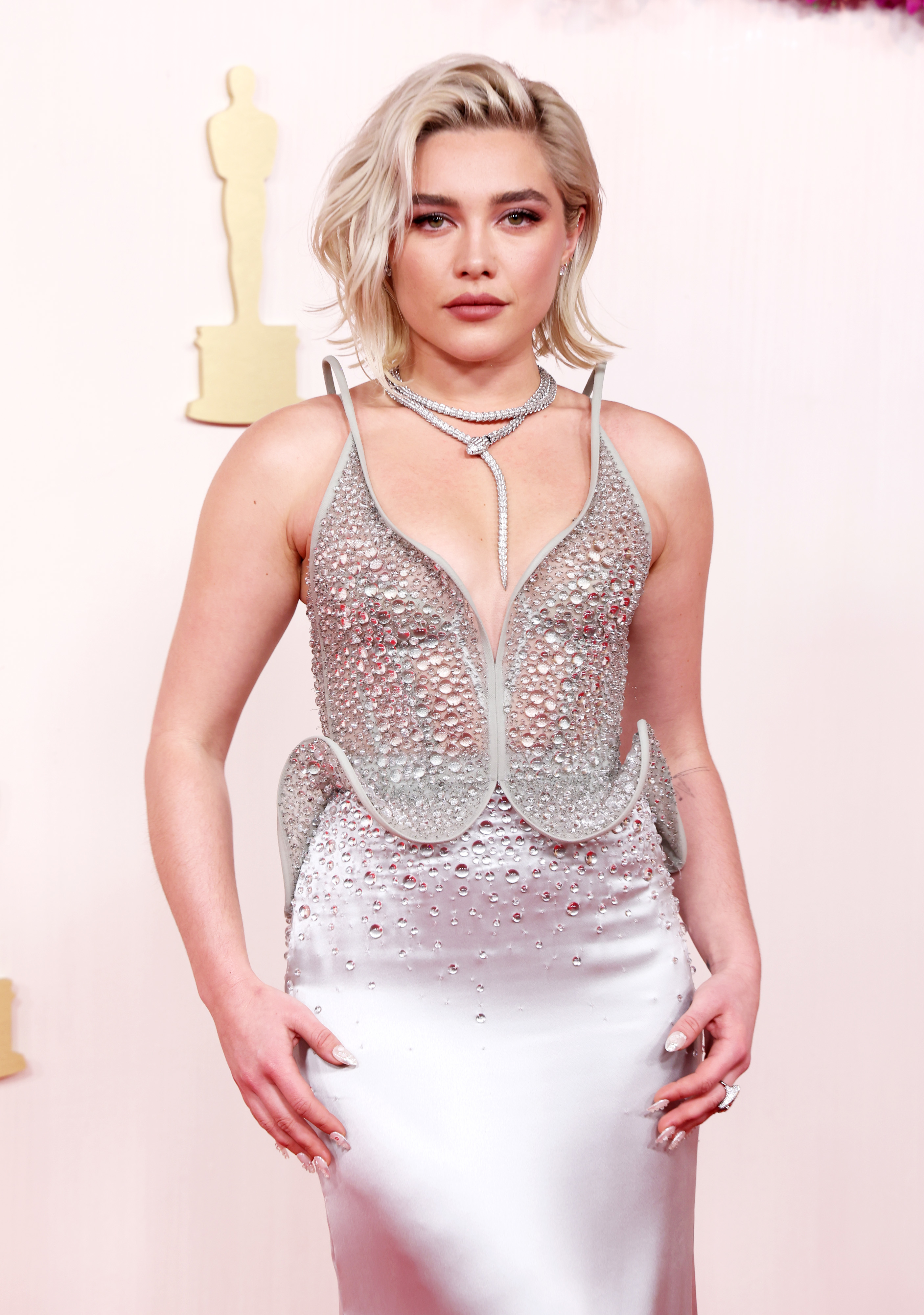 Florence Pugh poses on the red carpet wearing a shimmery gown with a structured, sparkling top and a fitted, satin-like skirt