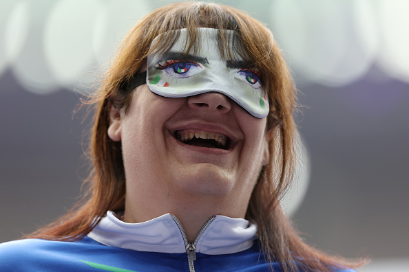 A person smiles while wearing a mask resembling wide cartoon eyes over their own eyes