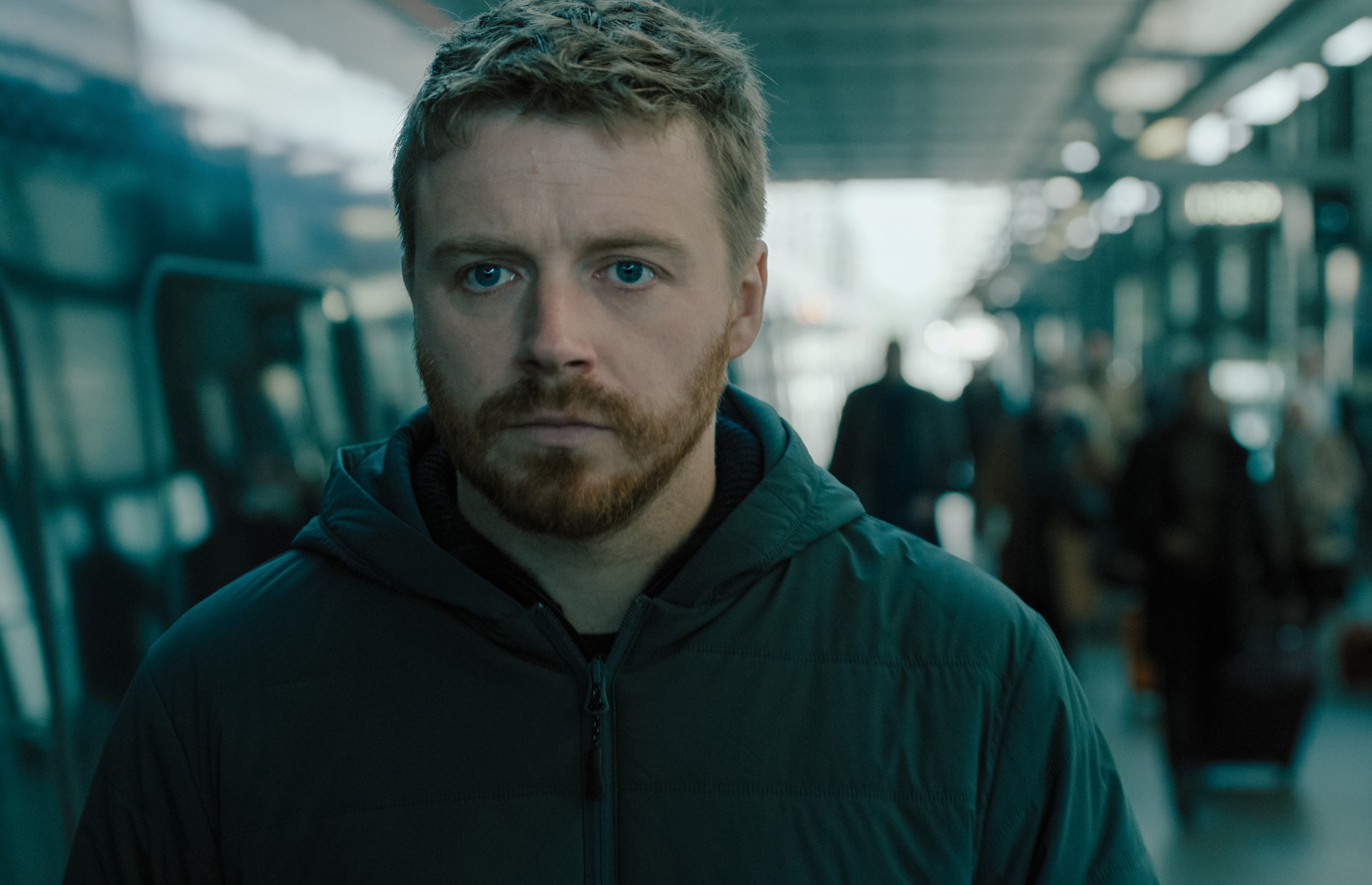 Jack Lowden walking through a train station in a scene from "Slow Horses"