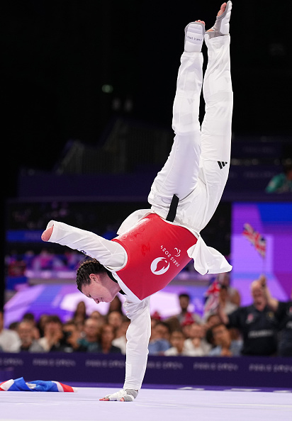 Taekwondo athlete performs a one-handed handstand during a competition