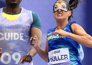 Brazilian paralympian Thalita Simplicio running with her guide at the World Para Athletics Championships, with Muller bib and superhero face paint