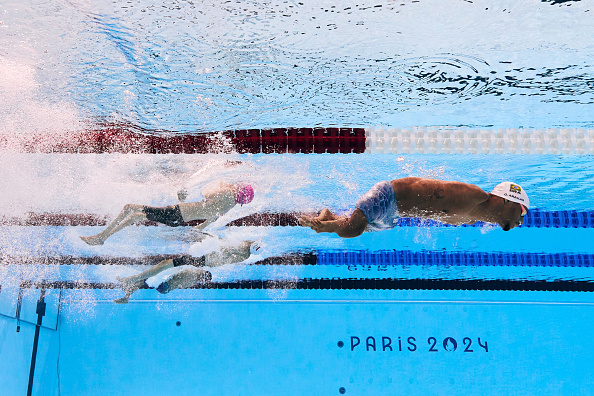 Swimmers in competition at the Paris 2024 aquatic event, mid-race, captured underwater. The image highlights their streamlined technique