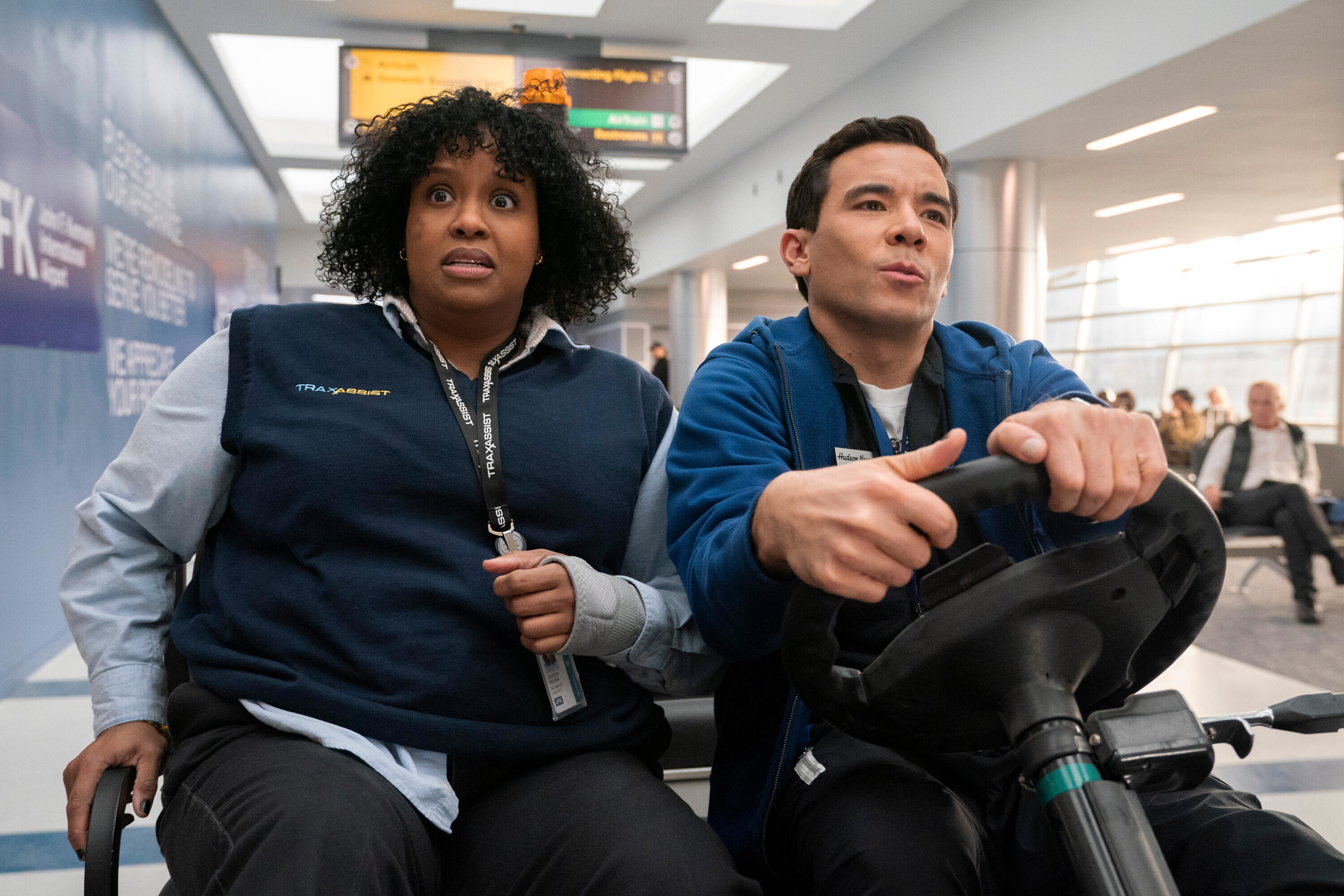 Natasha Rothwell and Conrad Ricamore driving through an airport in a golf cart in a scene from "How to Die Alone"
