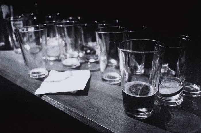 Multiple empty and half-filled beer glasses are lined up on a counter next to a crumpled napkin, suggesting a lively social gathering. No people are visible