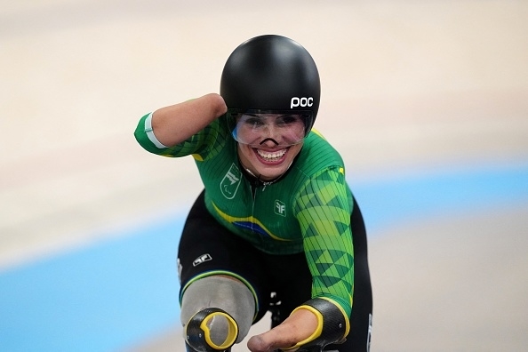 Paralympic cyclist Sarah Storey, in a racing outfit with a helmet, celebrates during a track event