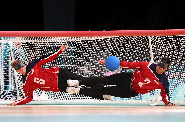 U.S. Paralympians Calahan Young (#8) and Matt Simpson (#2) in action during a goalball match, wearing red jerseys and eye masks