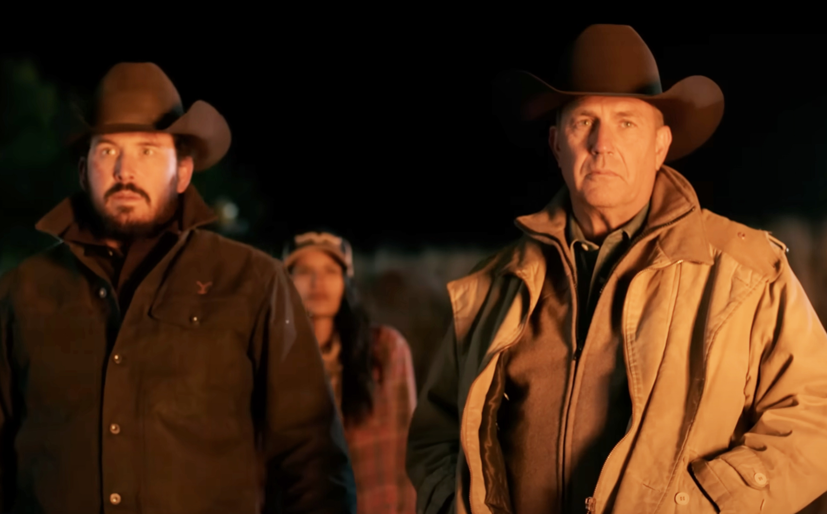 Cole Hauser, Kevin Costner in cowboy hats and jackets, standing outdoors at night