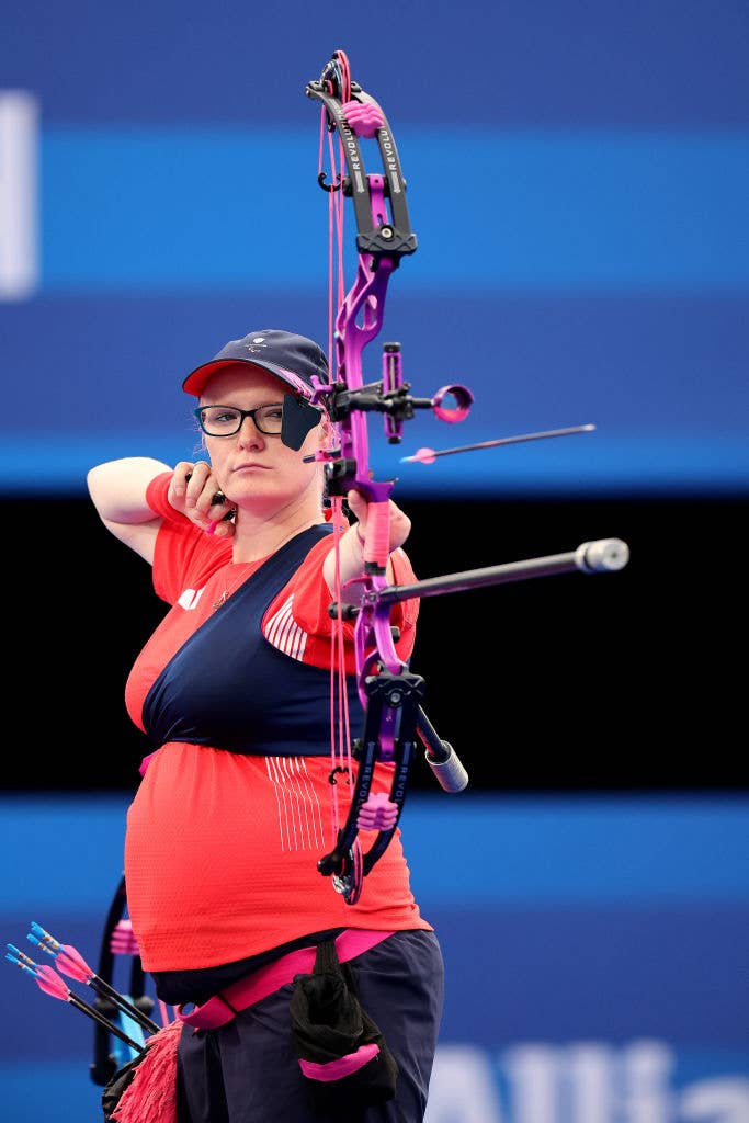 Jodie Grinham in sportswear is focused on aiming a bow during an archery competition