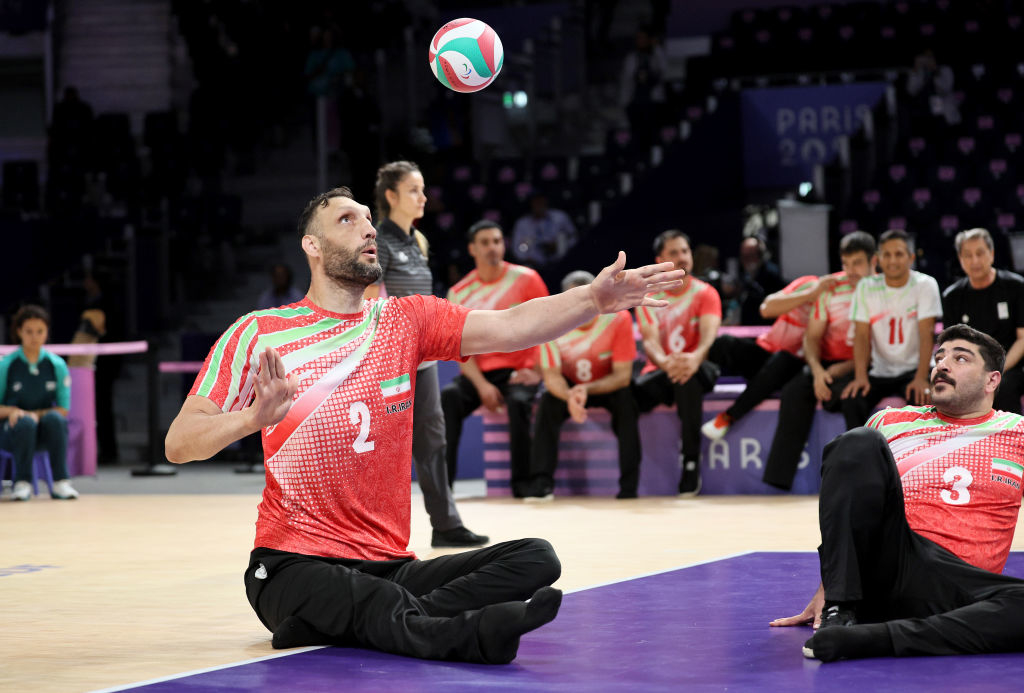 Morteza Mehrzadselakjani with jersey number 2 reaching for the ball during a game, while other players sit on the sidelines