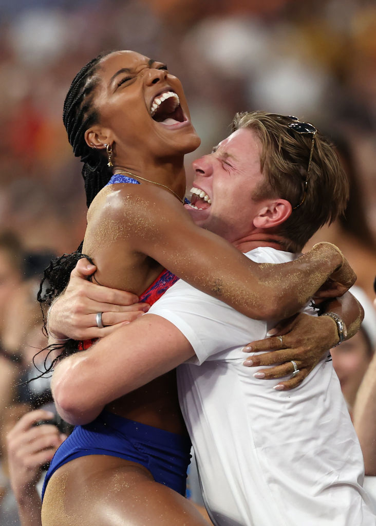 Tara Davis-Woodhall, wearing sports wear, celebrates in Hunter Woodhall's arms