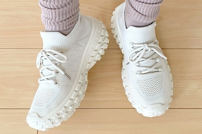白いスニーカーとグレーの靴下を履いた人物の足元。