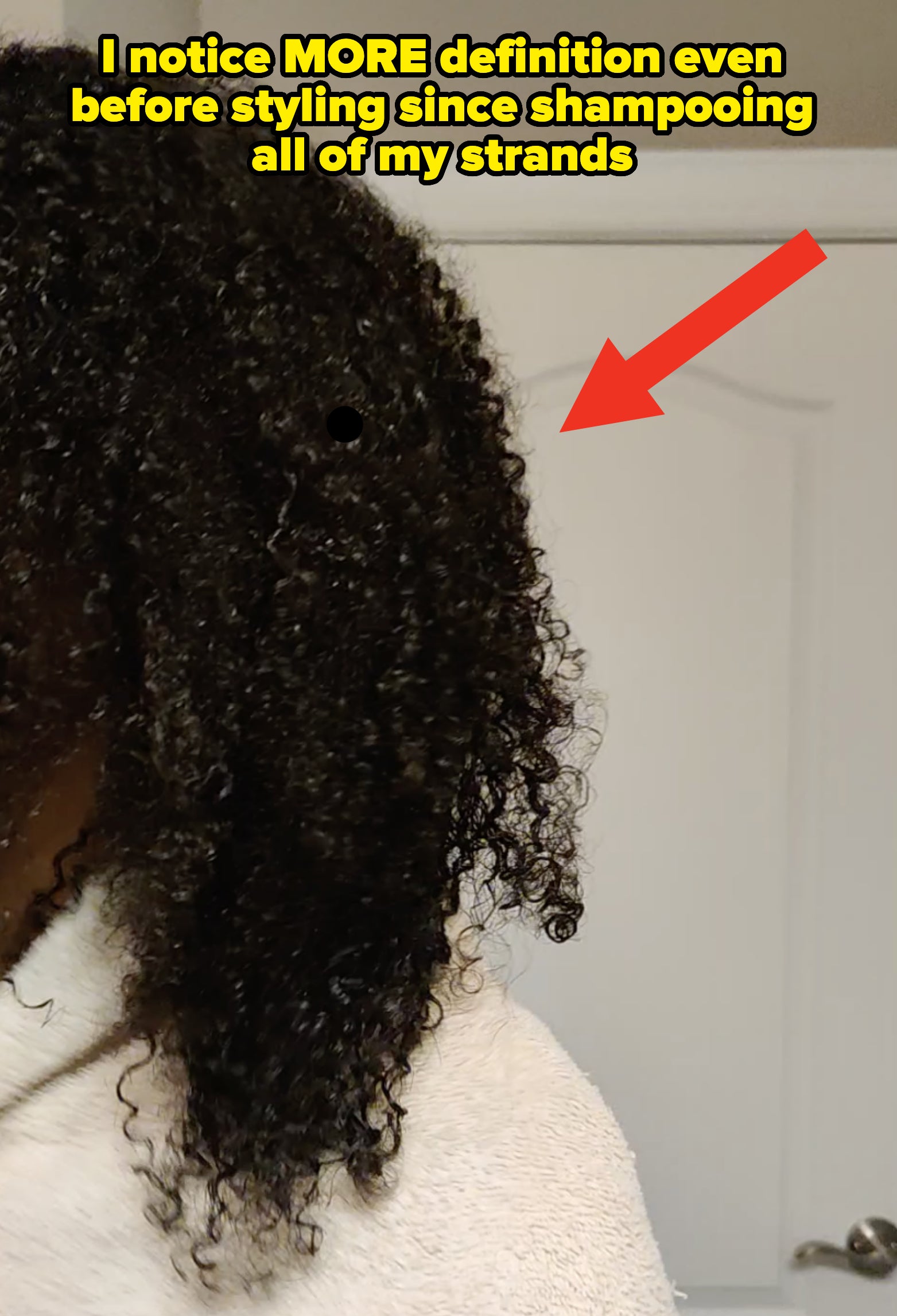 A close-up of my curly hair showing definition and texture; text reads: "I notice MORE definition even before styling since shampooing all of my strands"