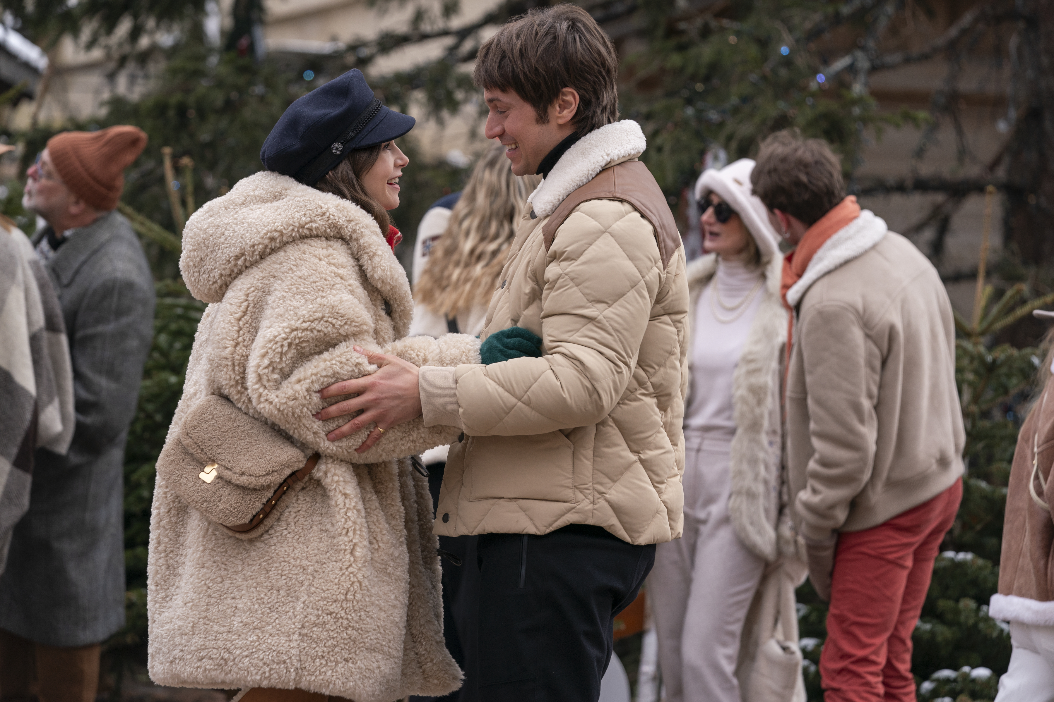 Emily and Gabriel embracing and wearing winter clothing in a scene from "Emily In Paris"