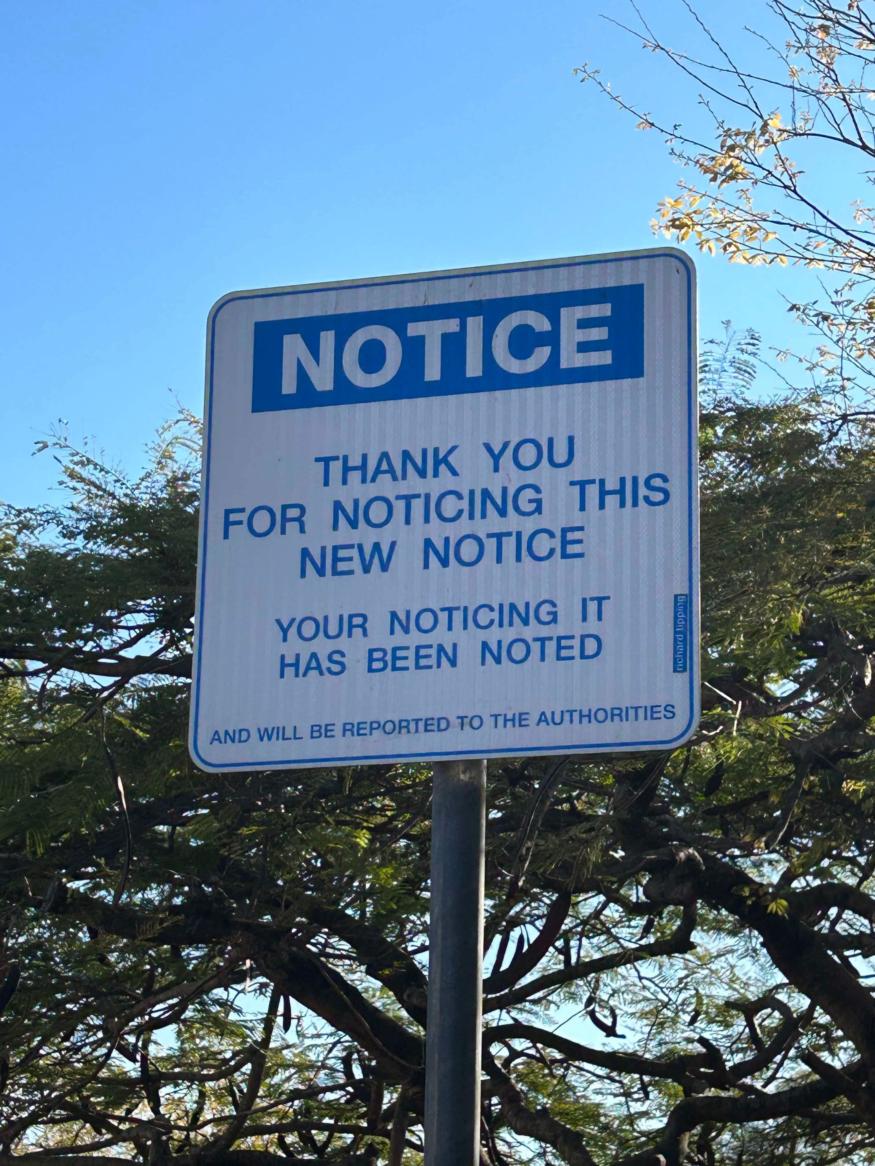 Sign reads: "NOTICE. Thank you for noticing this new notice. Your noticing it has been noted and will be reported to the authorities."