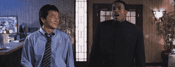 Jackie Chan and Chris Tucker share an amusing moment in a scene from the movie "Rush Hour." They both appear to be inside a building