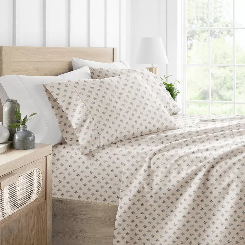 A neatly made furniture  with patterned sheets and pillowcases successful  a modern   bedroom. The ambience is minimalistic with plants and decor connected  the nightstand