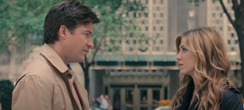 Jason Bateman and Jennifer Aniston face each other during a conversation scene in an urban setting