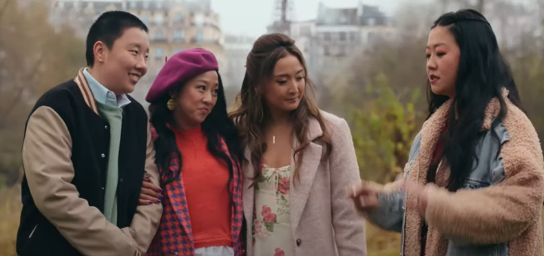 Four young adults are outdoors, talking and smiling.
