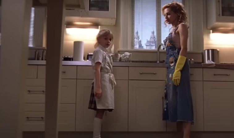 Dakota Fanning and Brittany Murphy stand in a kitchen scene from the movie "Uptown Girls." Dakota wears a school uniform; Brittany wears a dress with yellow gloves