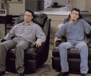 Joey Tribbiani and Chandler Bing sit in recliners, leaning back and relaxing in a living room